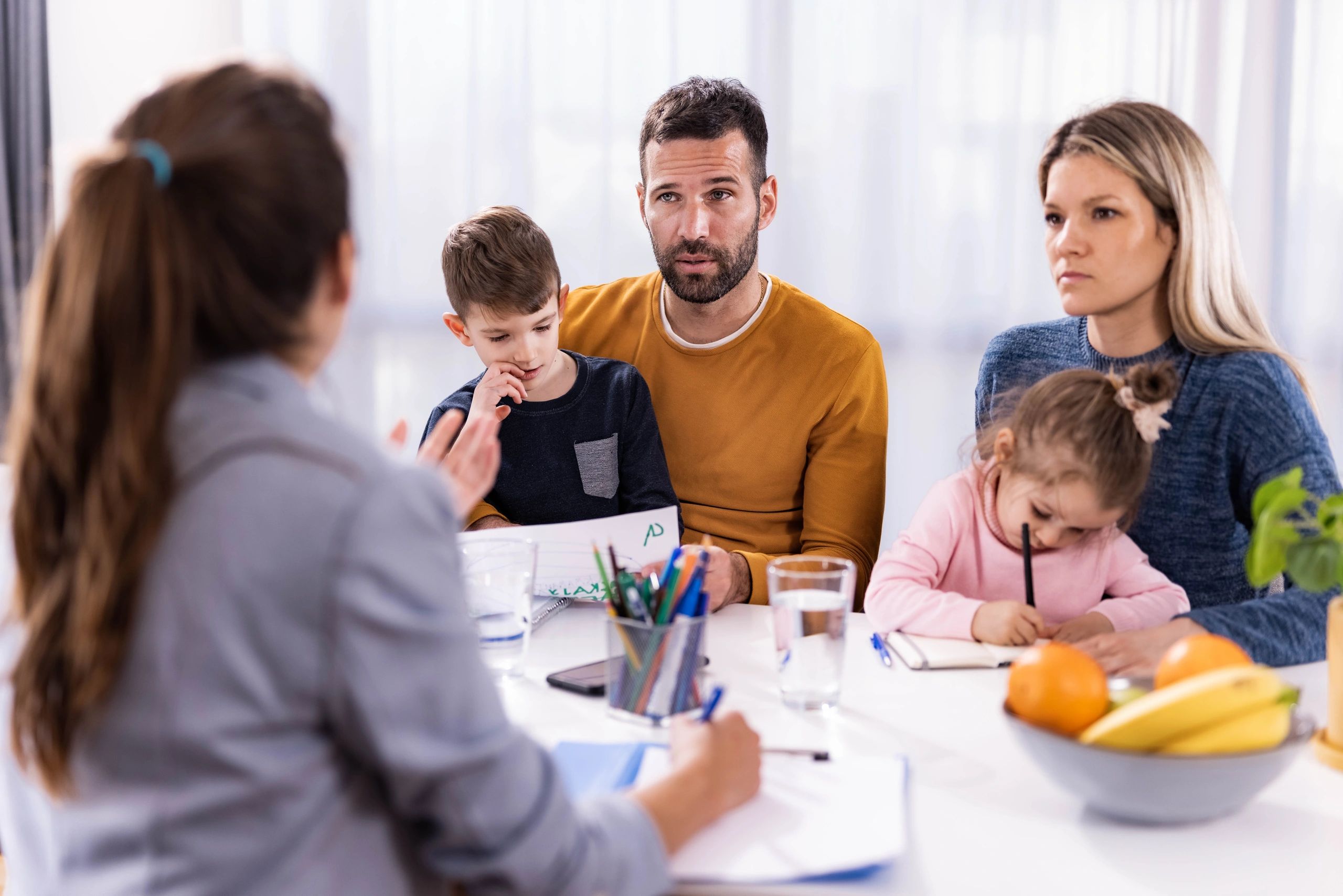 Familia en sesión de terapia conversando con su terapeuta en un consultorio